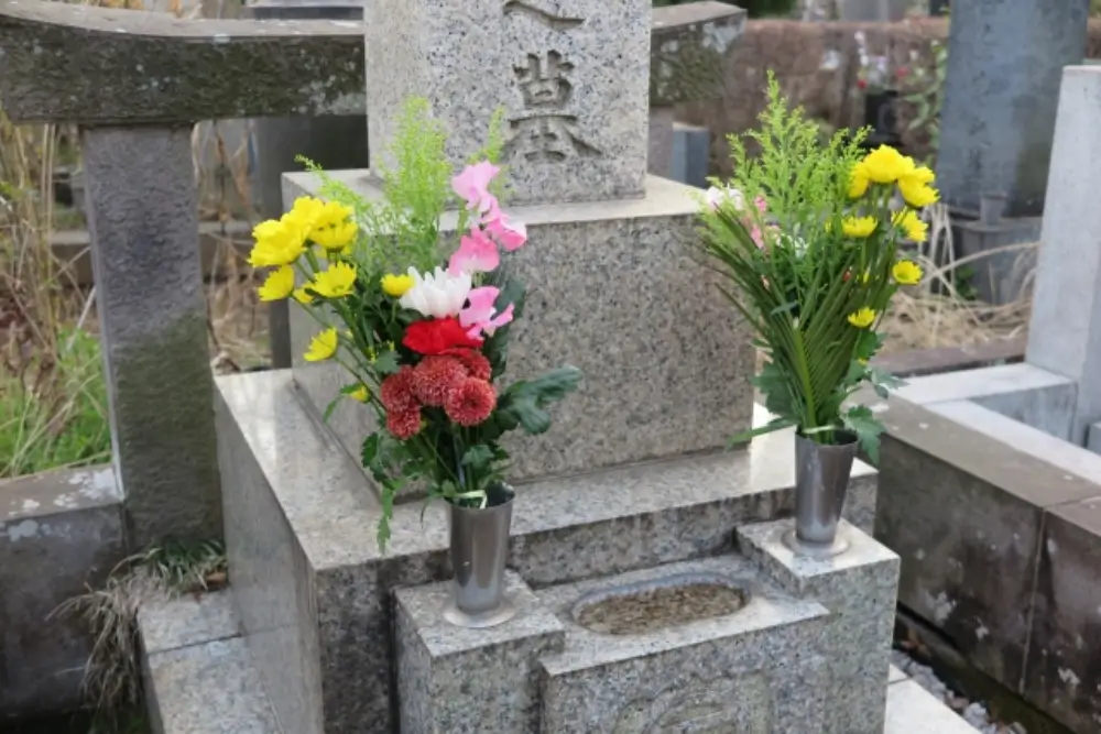 お墓の花立に色とりどりの供花が供えられている様子