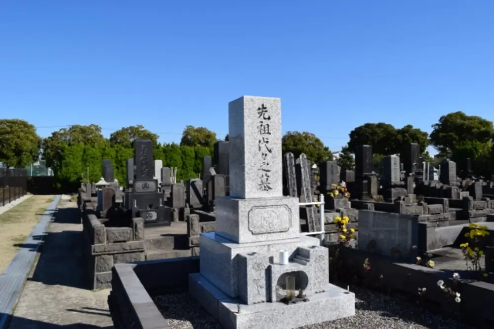 晴天の下に建つ先祖代々の墓石と周囲の墓地の風景