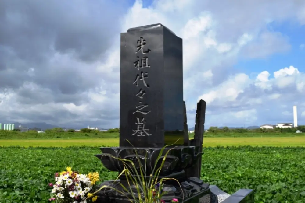 青空の下、田園に建つ黒御影石の立派な墓石