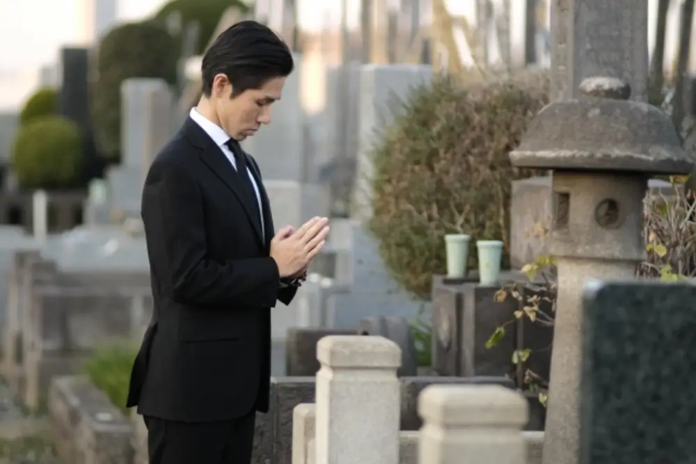 前で手を合わせる喪服姿の男性