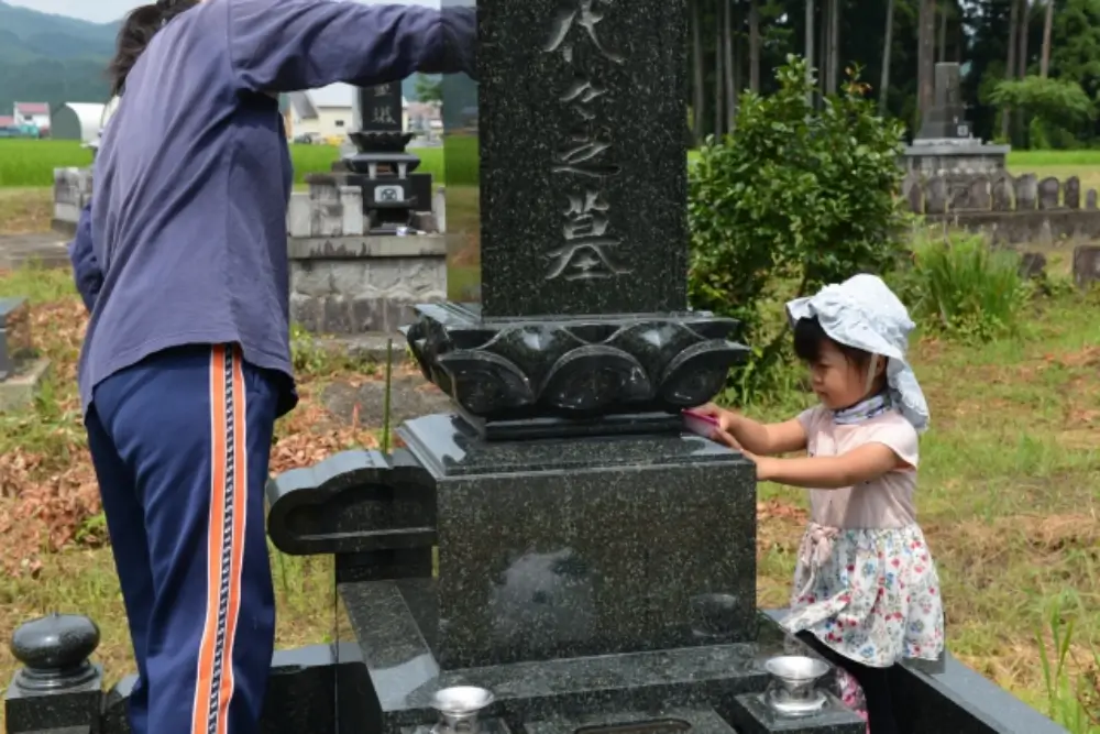 子どもが一緒にお墓を掃除している微笑ましい場面