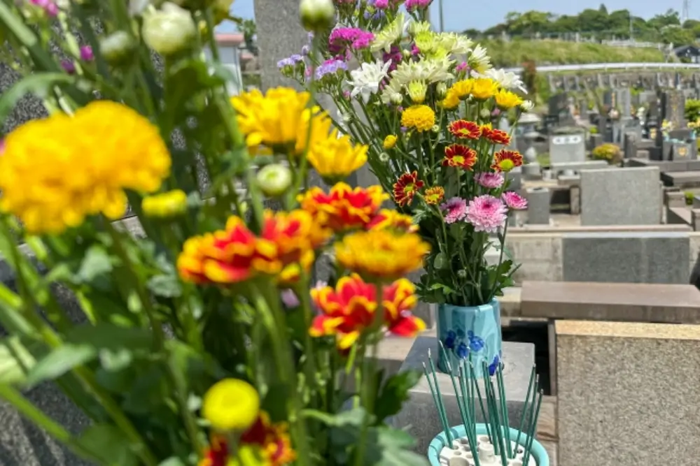 墓前に供えられた色とりどりの菊の花と線香