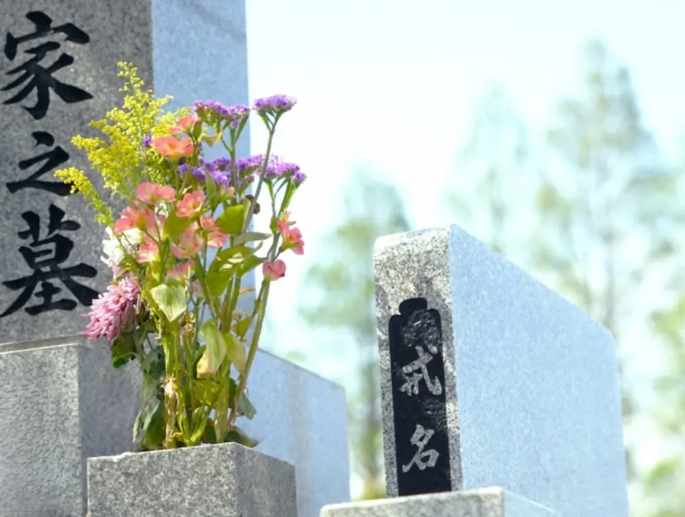 「家之墓」と刻まれた墓石と供えられた色とりどりの花のアップ写真