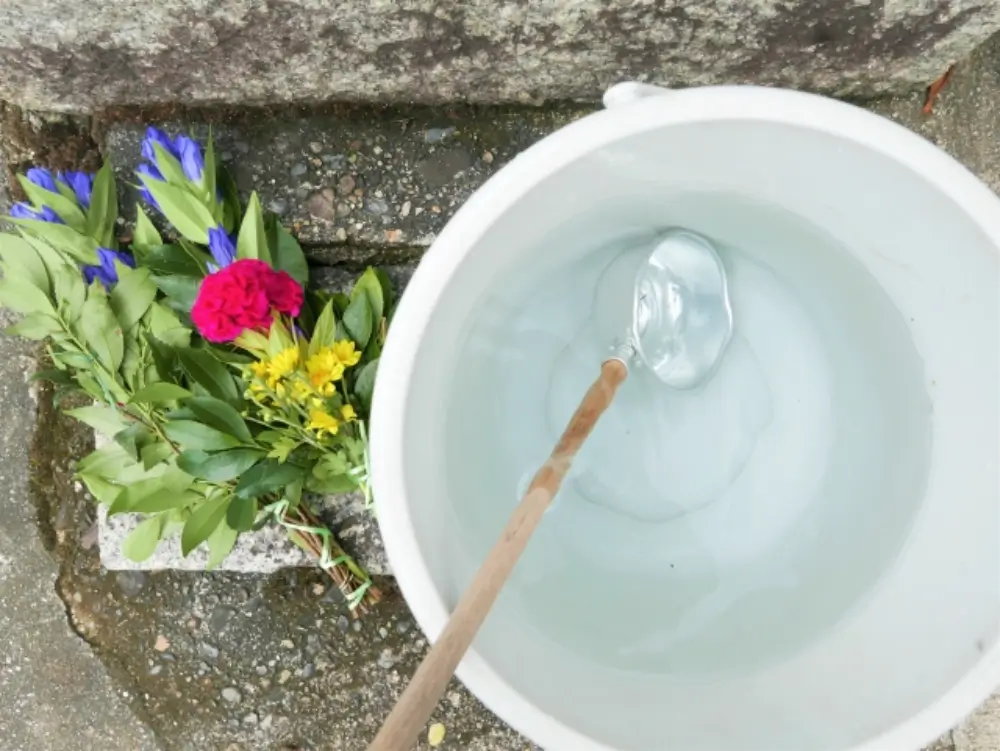 お墓参りの準備でバケツに花と柄杓を入れている様子