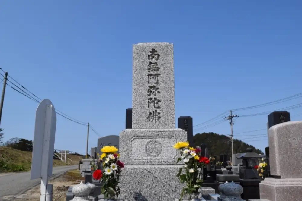 「南無阿弥陀仏」と刻まれた墓石と供えられた花々