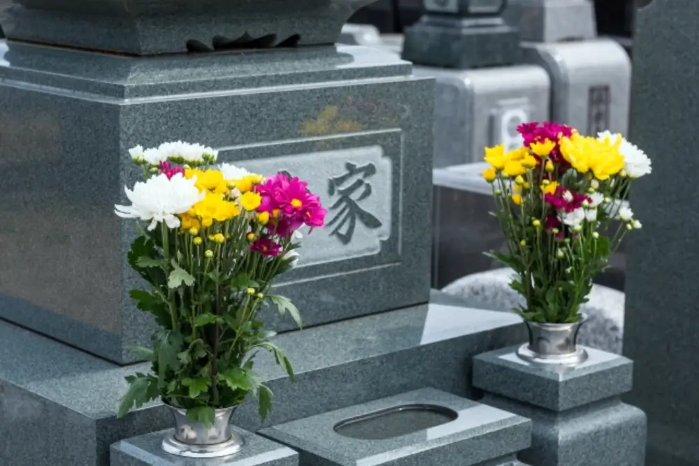 墓石の前に白・黄・ピンクの菊がきれいに供えられている様子