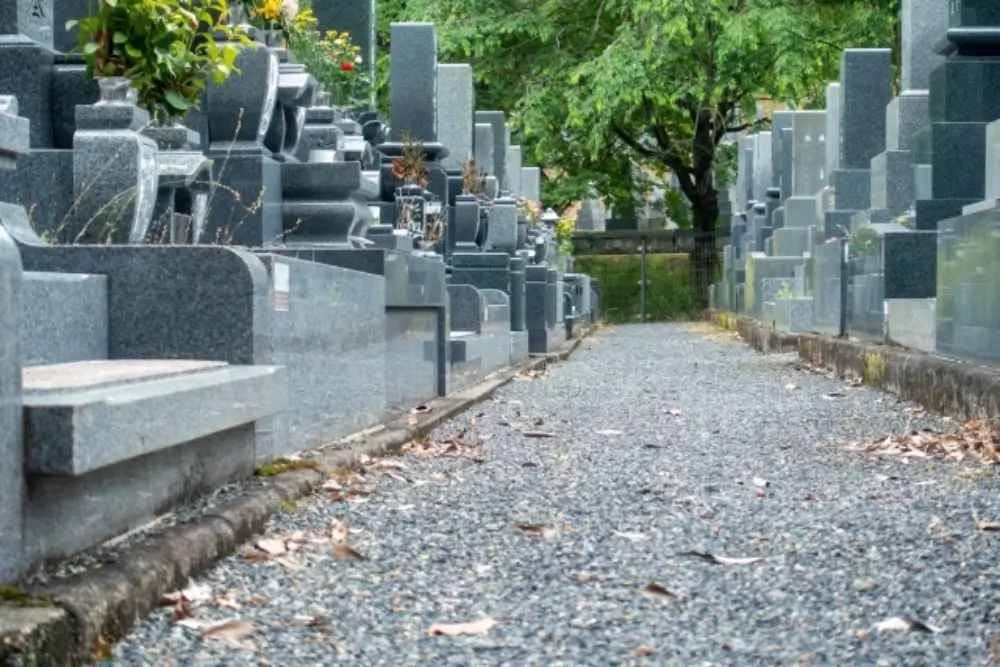 墓石が並ぶ墓地の通路、落ち葉が敷かれた静かな参道