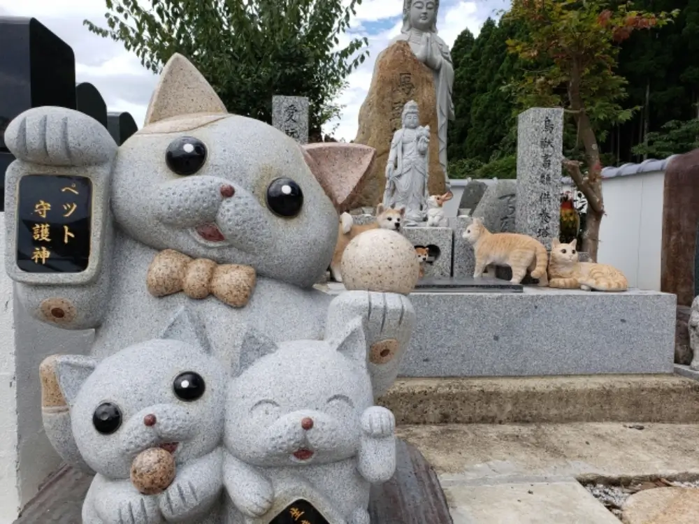 ペット供養の墓地に並ぶ猫の石像と「ペット守護神」の像