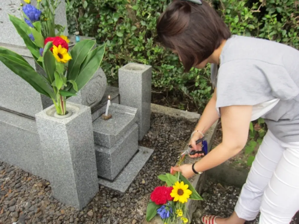 お墓に供える花を準備する女性の後ろ姿